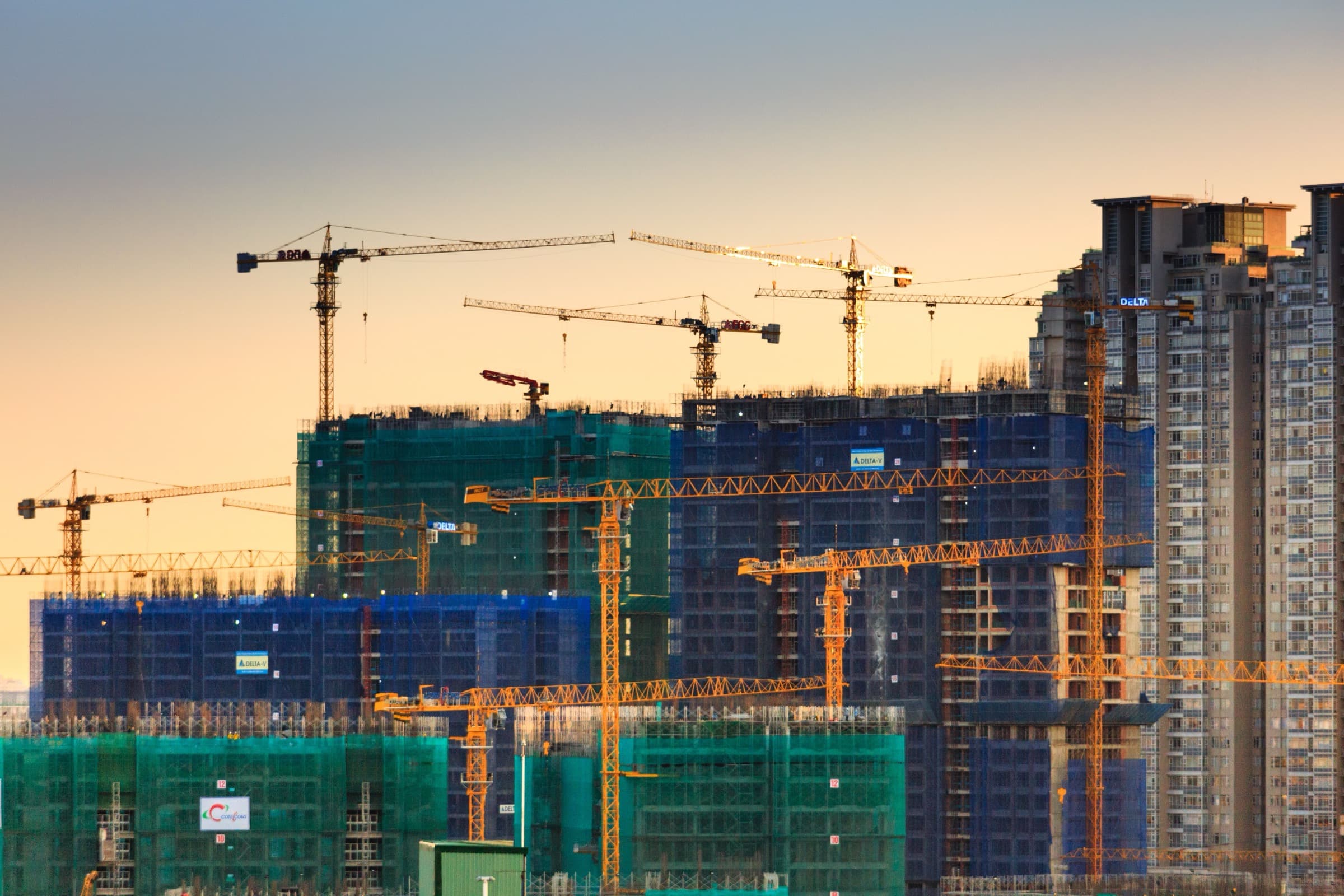 Tower cranes over buildings under construction at dusk