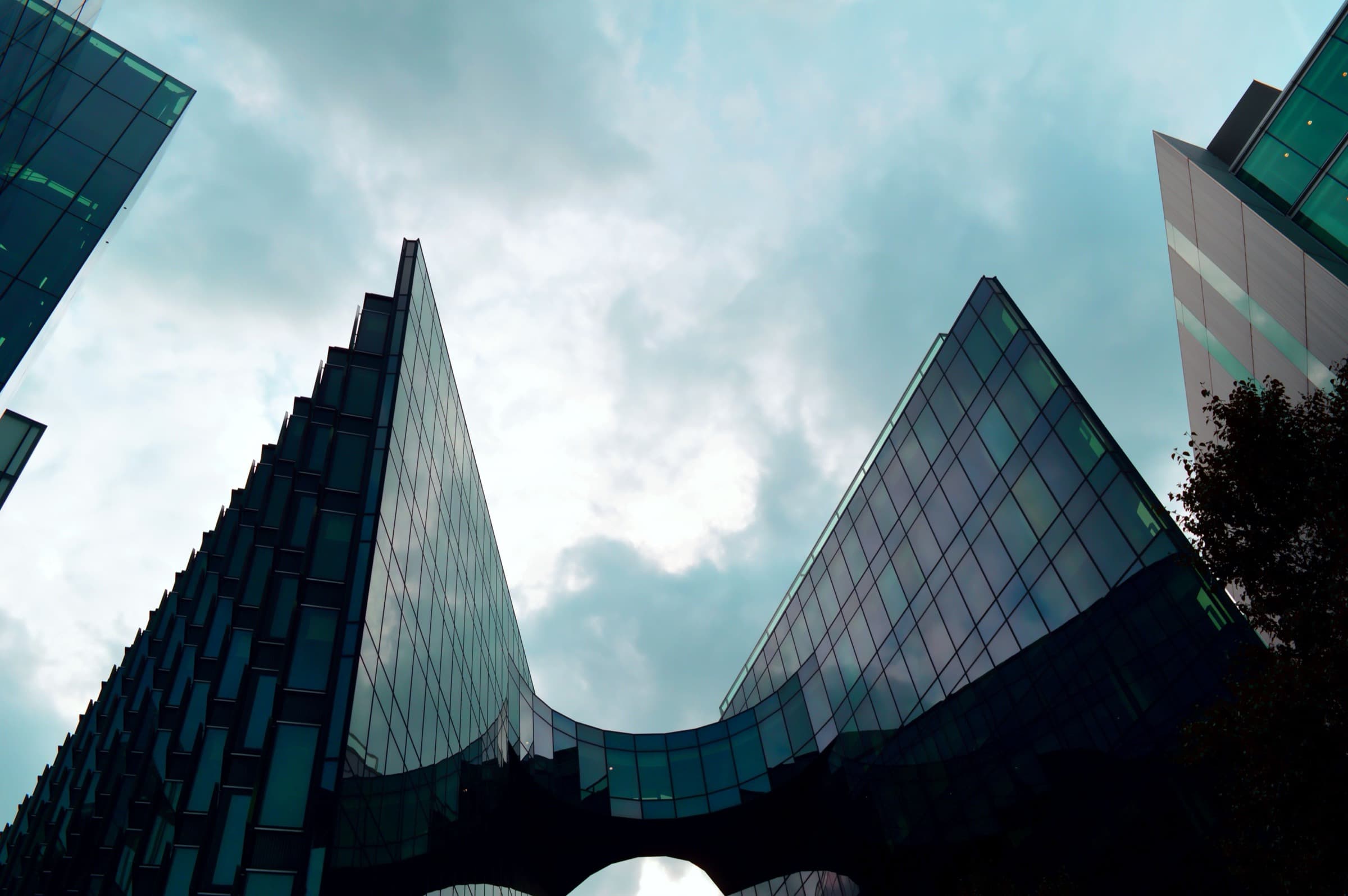 Glass towers seen from below against a moody sky
