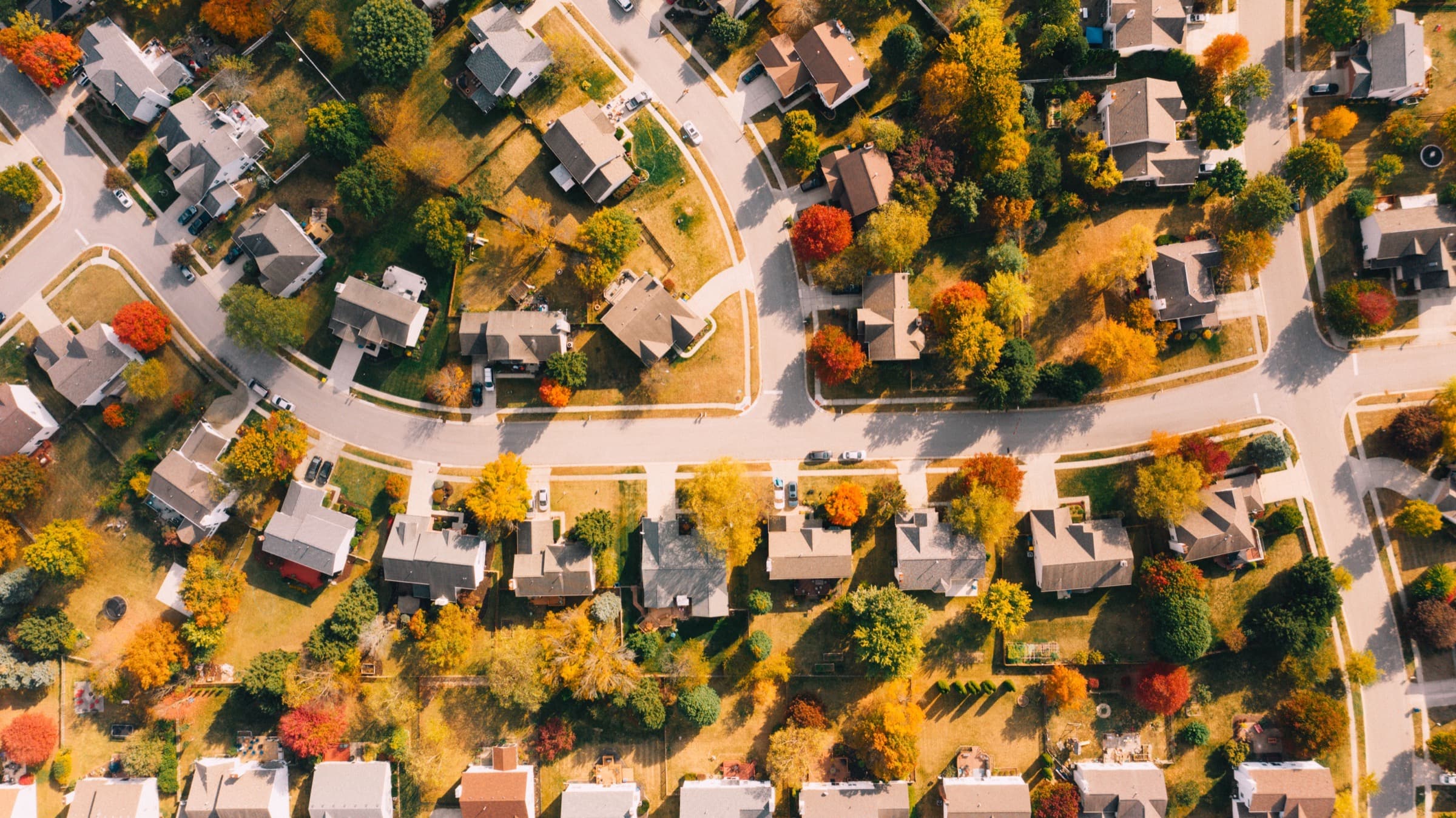 Aerial view of a neighborhood in autumn, streets curving between houses
