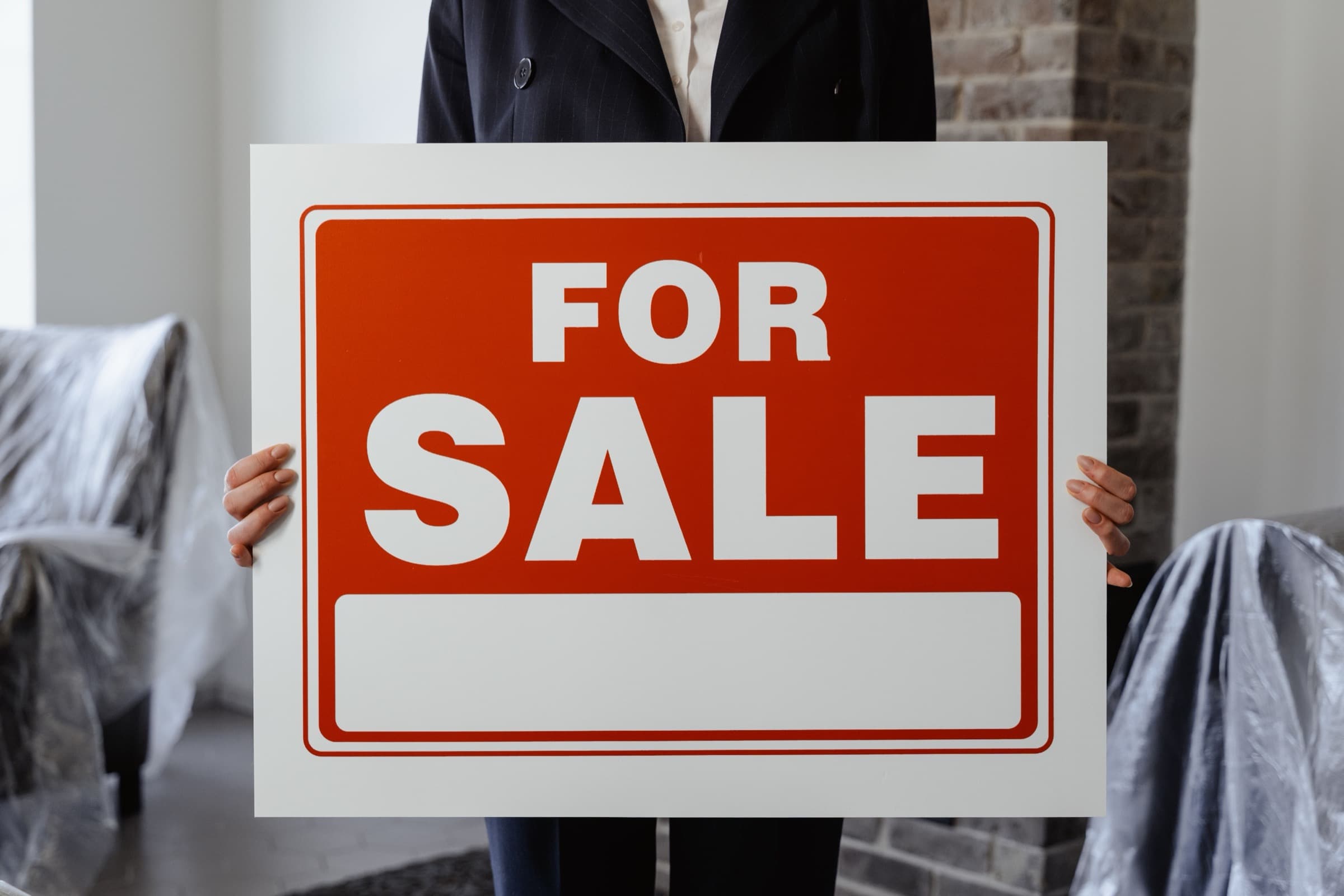 An agent holding a For Sale sign